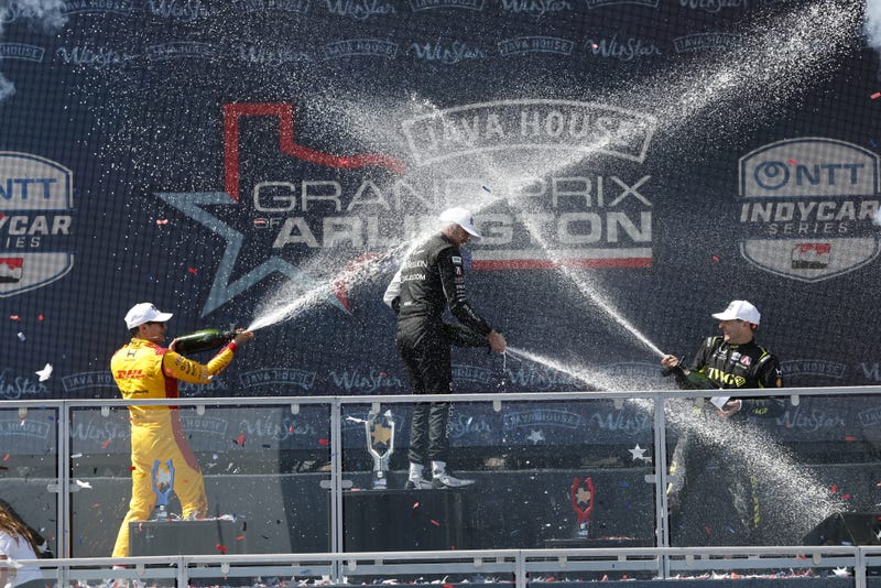 ARLINGTON, TEXAS- MARCH 15: #27: Kyle Kirkwood, Andretti Global Honda, #10: Alex Palou, Chip Ganassi Racing Honda, #26: Will Power, Andretti Global Honda celebrate on the podium with champagne during the NTT INDYCAR Series Java House Grand Prix of Arlington on March 15, 2026 in Arlington, Texas. (Photo by Michael L. Levitt/Lumen via Getty Images)
