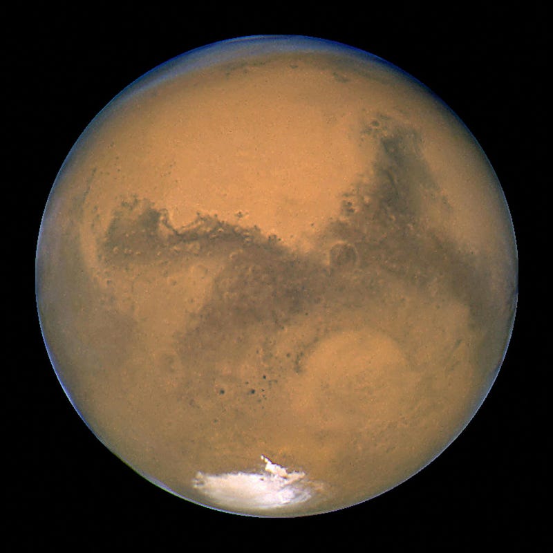 This image released August 27, 2003 captured by NASA's Hubble Space Telescope shows a close-up of the red planet Mars when it was just 34,648,840 miles (55,760,220 km) away. This color image was assembled from a series of exposures taken between 6:20 p.m. and 7:12 p.m. EDT August 26, 2003 with Hubble's Wide Field and Planetary Camera 2. The picture was taken just 11 hours before the planet made its closest approach to Earth in 60,000 years. Many small, dark, circular impact craters can be seen, attesting to the Hubble telescope's ability to reveal fine detail on the planet's surface. (Photo by NASA/Getty Images)
