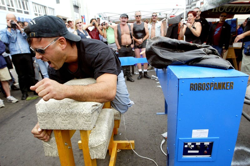 An unidentified man reacts after being spanked by the "Robospanker" spanking machine at the 20th Annual Folsom Street Fair September 28, 2003 in San Francisco, California.