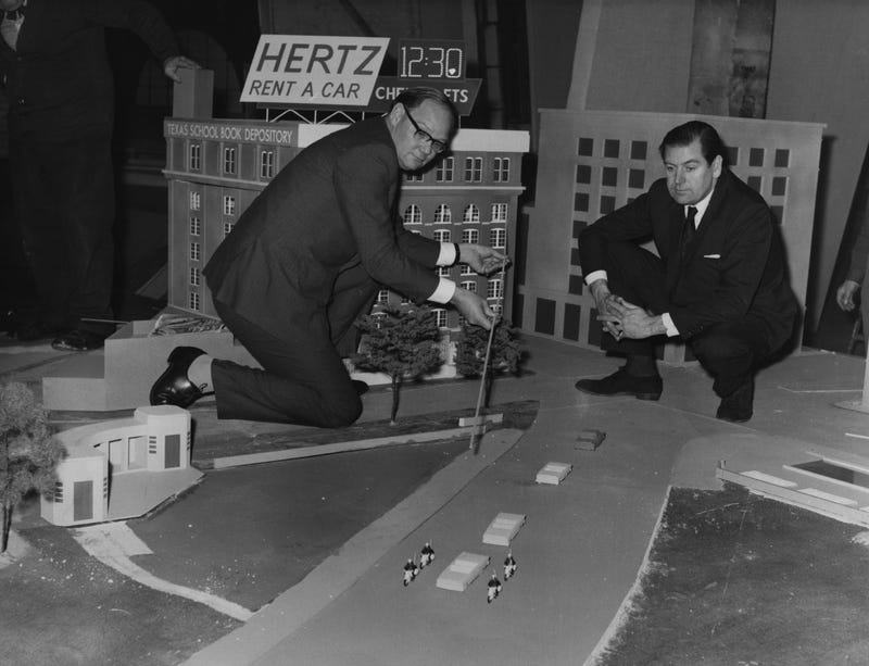 Cliff Michelmore pointing to the path of gun shots which killed President John F Kennedy, on a model reconstruction of Dealey Plaza, in Dallas, Texas.