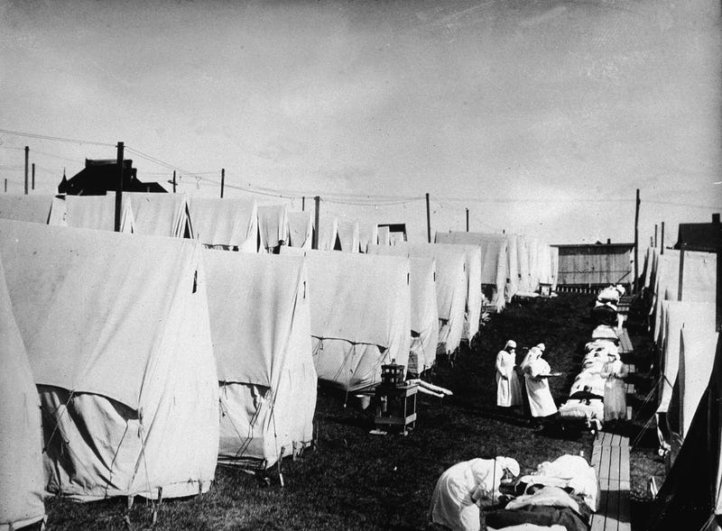 Nurses care for victims of the 1918 influenza pandemic outdoors amidst canvas tents in Lawrence, Massachusetts, 1918.