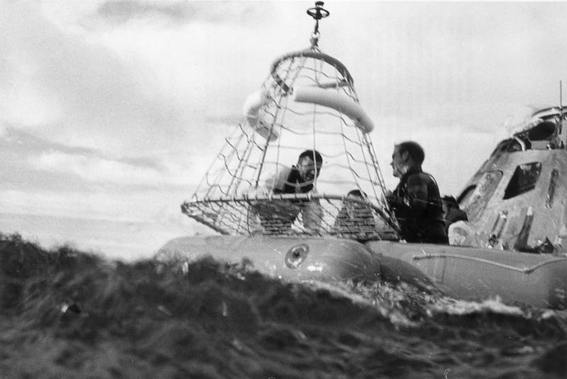 17th April 1970: Apollo XIII recovery operations in the South Pacific. Astronaut and lunar module pilot Fred W Haise Jr is about to be hoisted up to a recovery helicopter from the USS Iwo Jima. Awaiting their return are command pilot John L Swigert Jr (centre) and commander James A Lovell Jr (right). A member of an underwater demolition team assists with the recovery. 