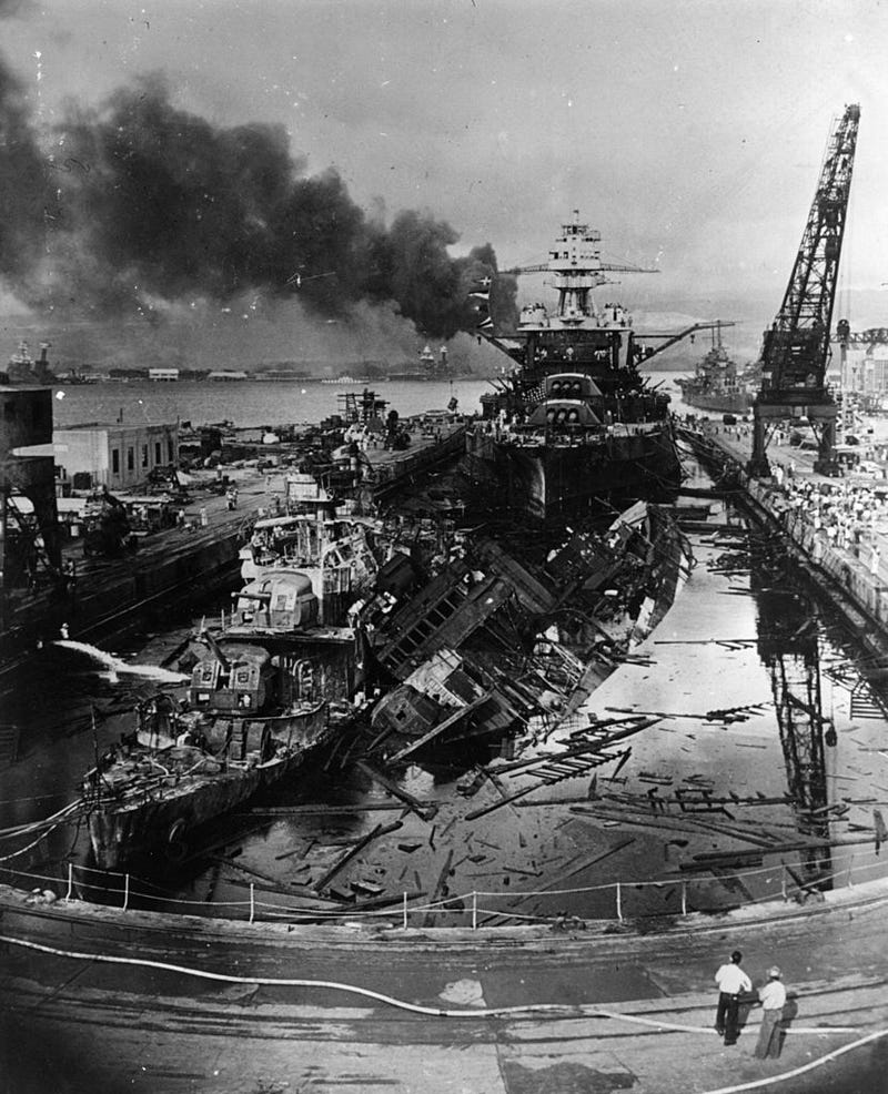 December 1941: Visible in the centre distance is the capsized USS Oklahoma with USS Maryland alongside.