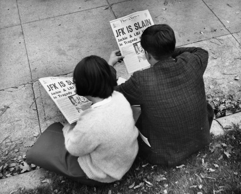 Two people in Lafayette Park, Washington, reading the newspaper reports of President John F Kennedy's assassination.