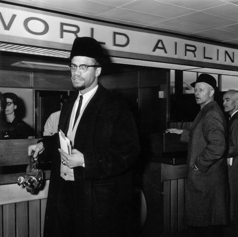 Black Muslim activist Malcolm X (1925 - 1965) arrives at London Airport carrying a portable cinecamera.
