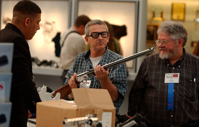 Conventioneers look over a rifle on display at the 133rd National Rifle Association National Convention