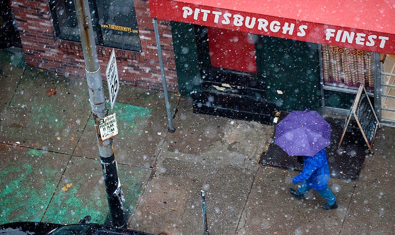 A pedestrian walks amidst the snow showers along Penn Ave