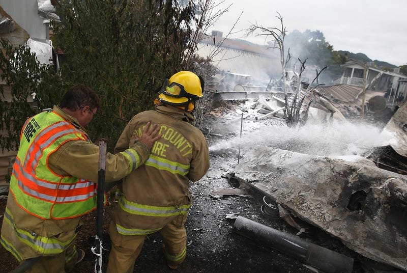 Firefighters spray foam.