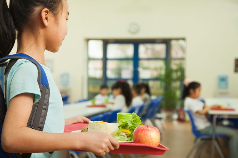 Child holding her lunch in a lunch room. 
