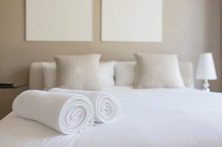Hotel room bed with rolled up towels set on bed