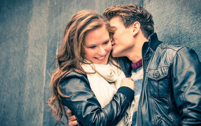 Man whispering into woman's ear