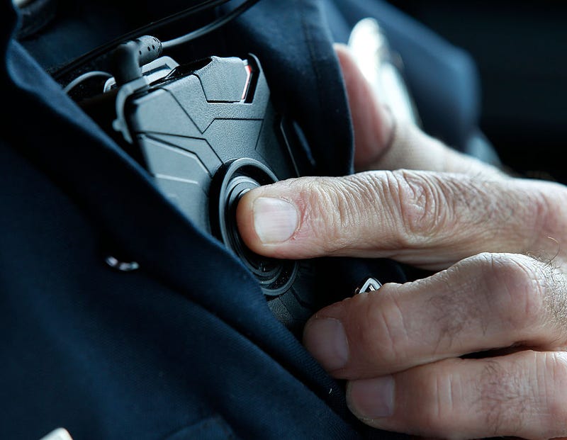 An officer starts a body camera recording by pressing a button on his chest.