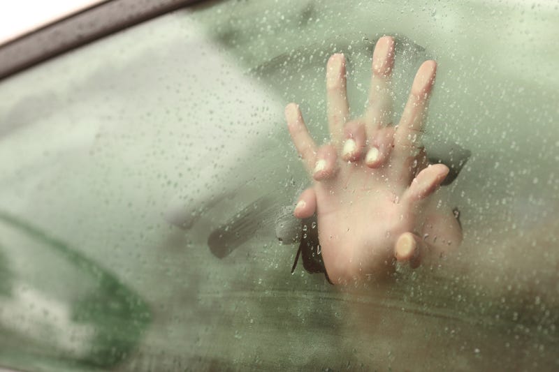 Hands clasped in a car window.