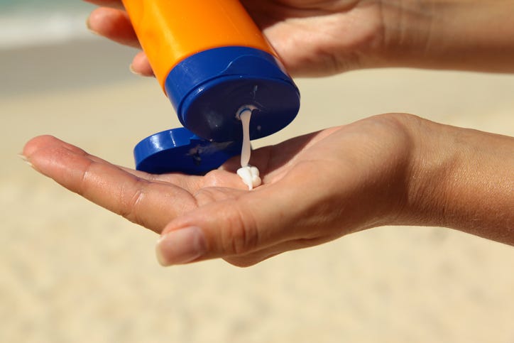 Person at the beach using sunscreen.