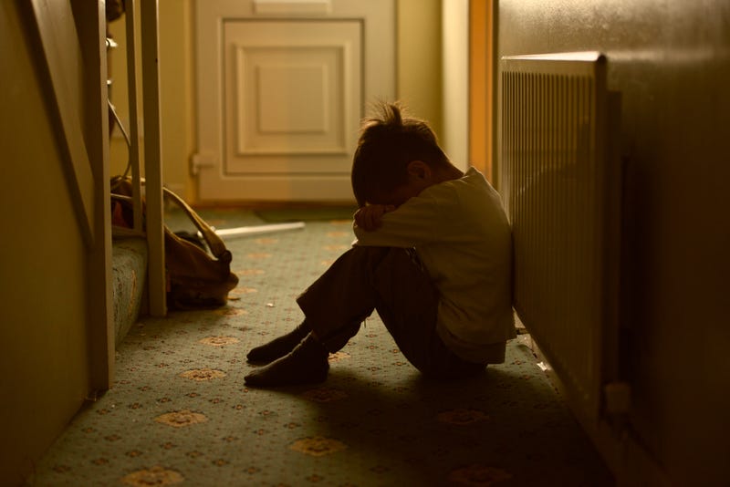 sad child with his head between his legs left alone at home