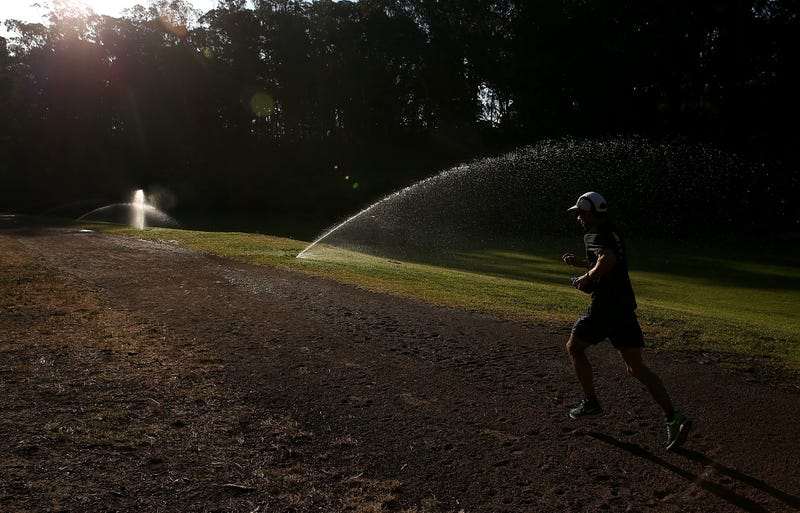 A jogger runs by sprinklers watering the lawn in Golden Gate Park on April 2, 2015 in San Francisco, California.