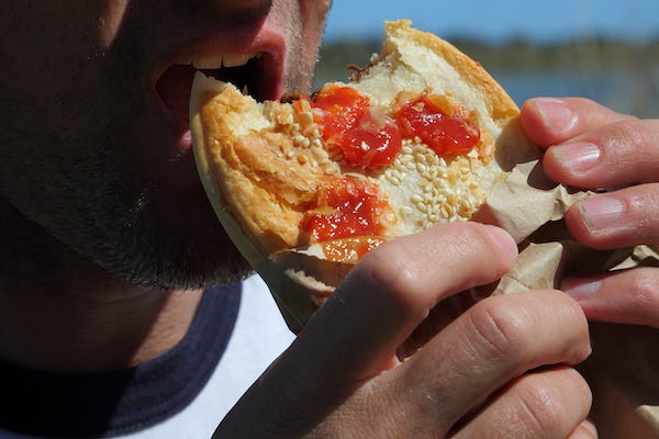 Man eating a meat pie topped with sauce