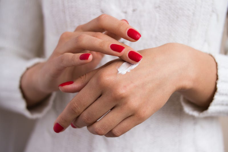 Woman's hands close up, applying cream to skin.