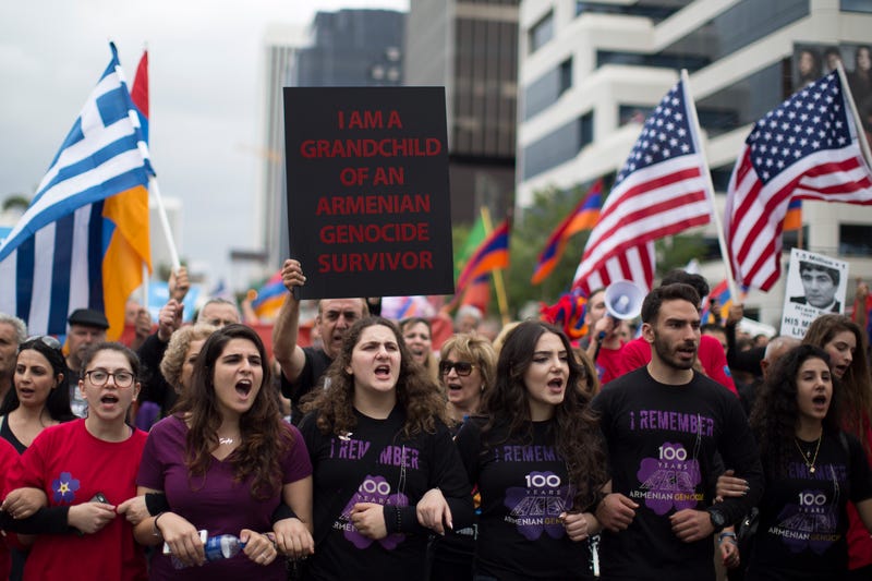 protesters linking arms wiht a sign that says i am a grandchild of an armenian genocide survivor