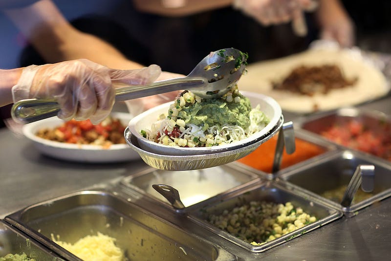 Chipotle restaurant workers fill orders for customers.