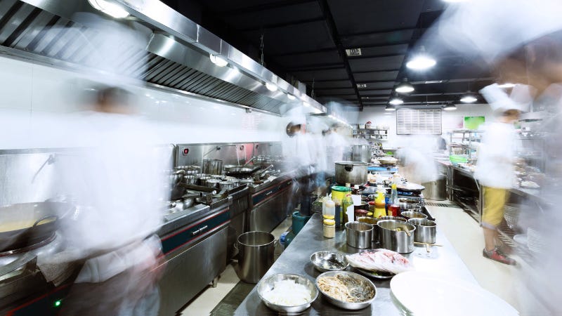 Time exposure of chefs bustling around inside a busy restaurant kitchen