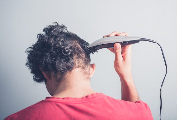 Young man cutting his hair at home 