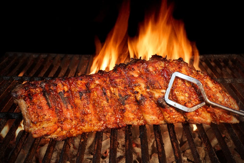 BBQ baby back pork ribs close-up on hot grill