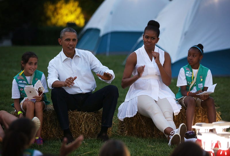 U.S. President Barack Obama (2nd L) and first lady Michelle Obama (3rd L), flanked by Daphnye Shell (L) of Peggs, Oklahoma, and Kennedi Pridget (R) of Maryland, participate in a campfire songs session with fourth-grade Girl Scouts during the first-ever White House Campout June 30, 2015 at South Lawn of the White House in Washington, DC. The first lady hosted the event, as part of her Let's Move! Outside initiative, for Girl Scouts to participate in activities to earn their Camper Badge, and to celebrate the release of the new Girls' Choice Outdoor badges