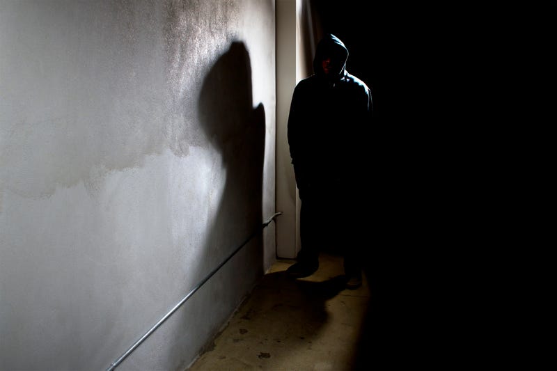 FILE: A person in a dark alley with a hood on.