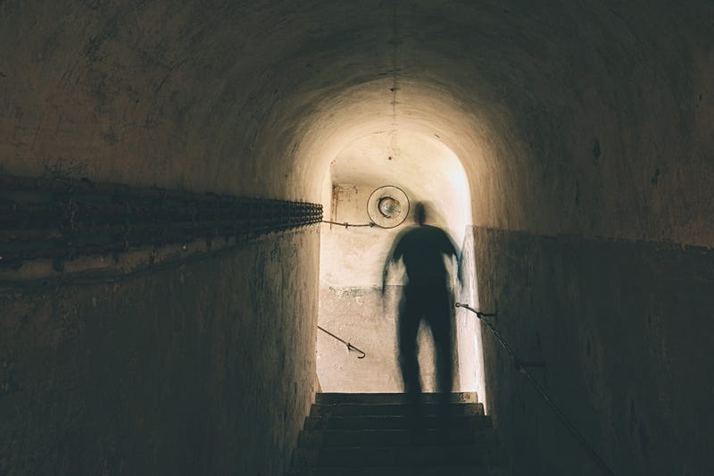 Man is walking through dark underground.