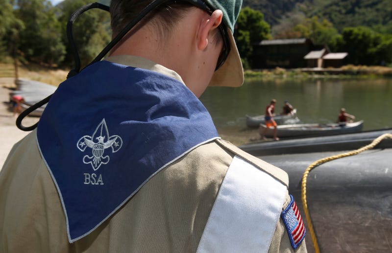 A Boy Scout works on a canoe at camp.