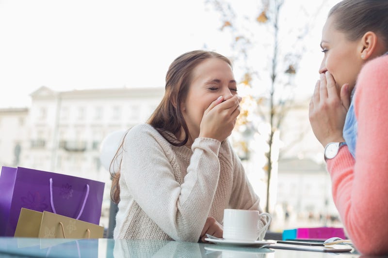 Happy women sharing secrets at outdoor cafe