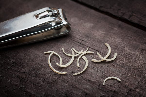 Nail clipper and nail clippings on wooden table
