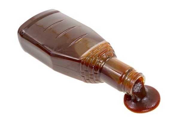Barbecue sauce bottle spilling on a white background