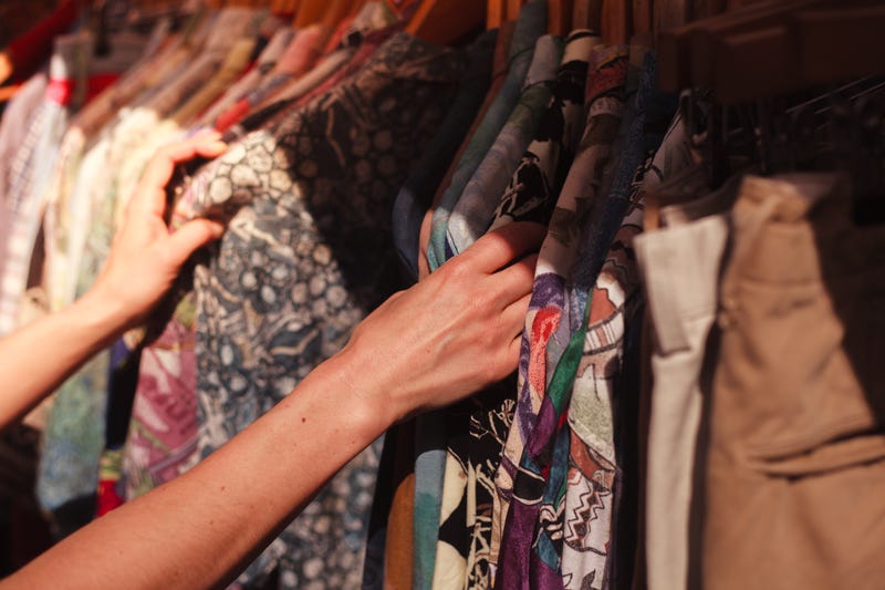 A young woman browses a rail of clothes at a street market.