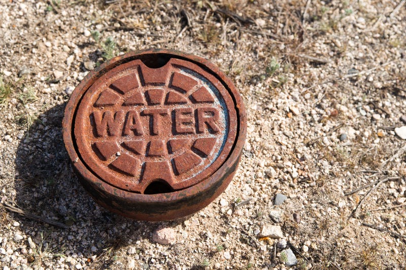 A rusted cast iron water main cover.