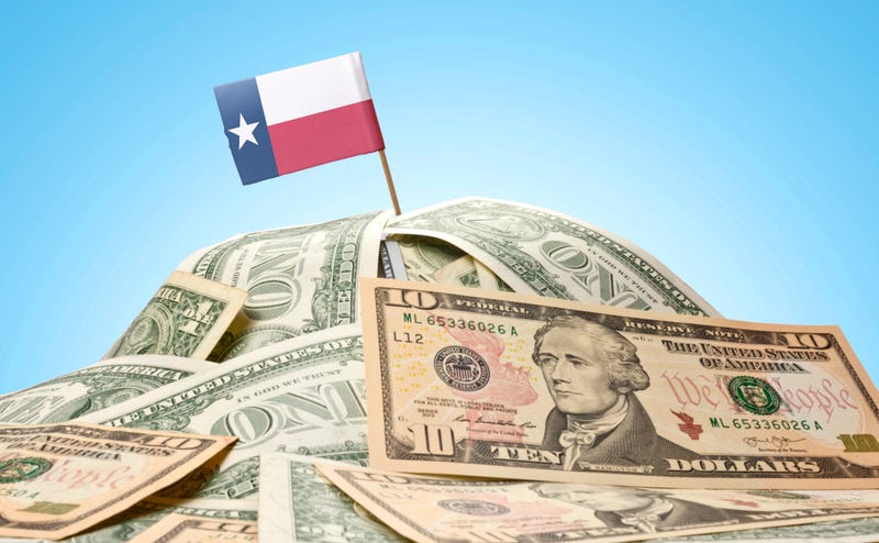 Stacks of money with the Texas State Flag planted at the top