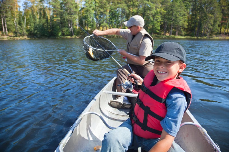 Young boy fishes with dad on the lake