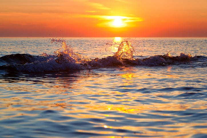 A wave splashes at sunset on Lake Michigan in Ludington State Park.