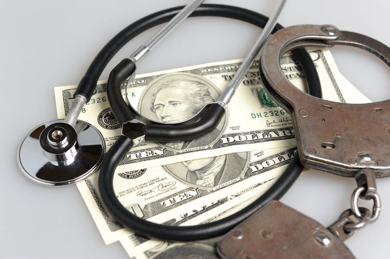 Stethoscope, handcuffs and money on gray background