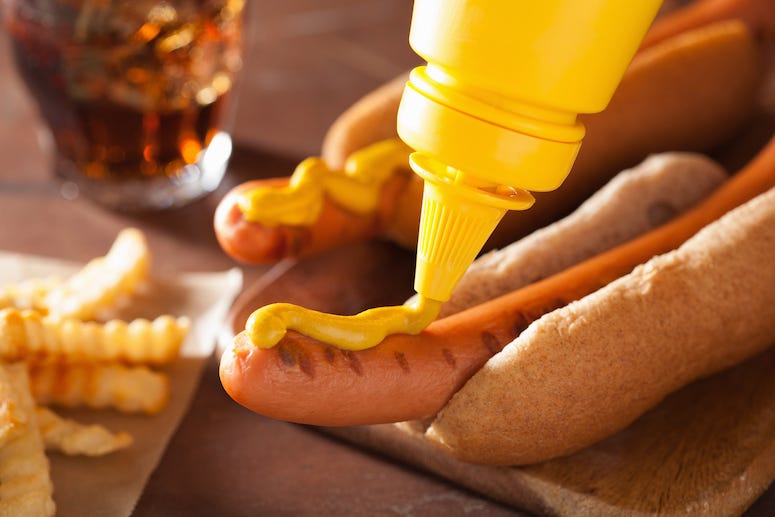 Applying mustard to a hot dog
