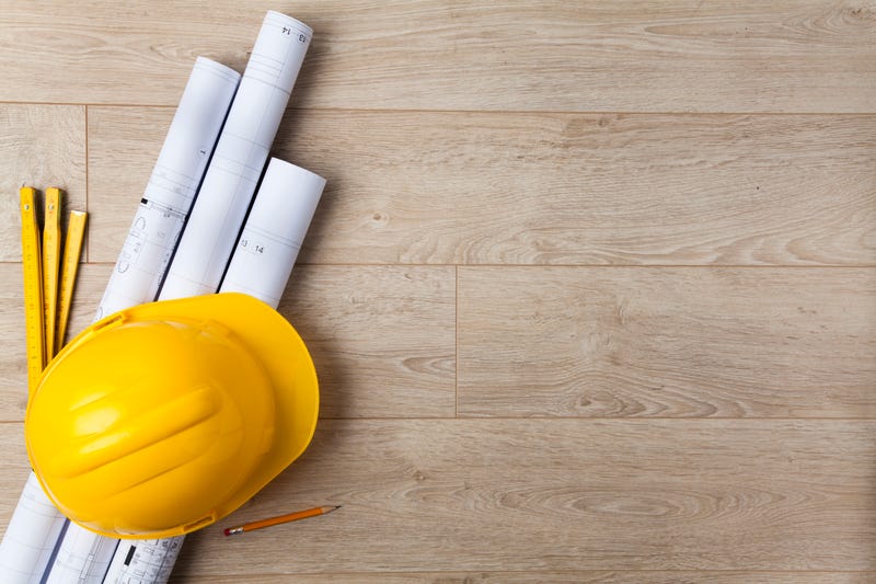 Yellow helmet with blueprints to wood background