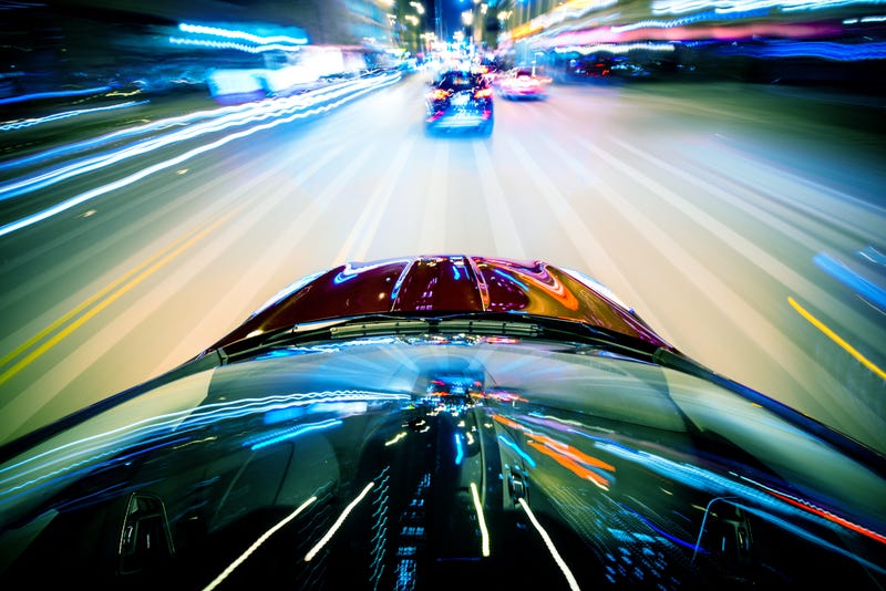 two cars speeding at night with blurred passing lights