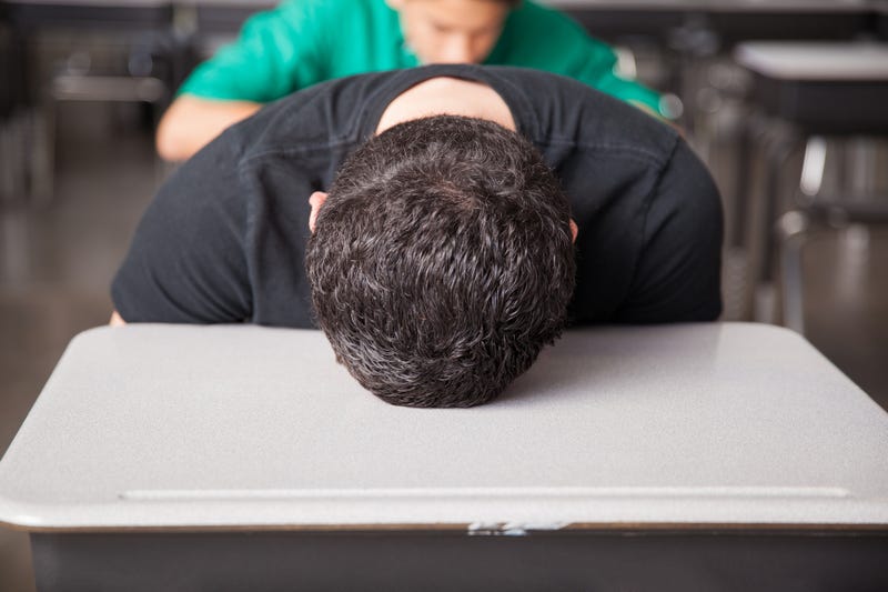 student with his head down on the desk