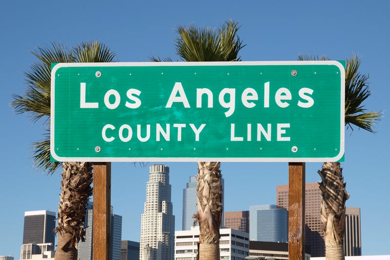 Los Angeles county line sign with downtown Los Angeles skyline in background.