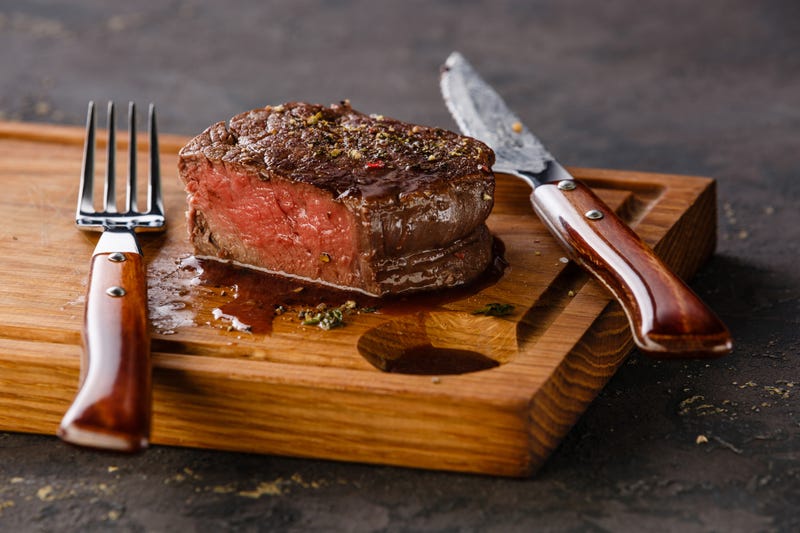 A close up of a steak on a plank of wood.