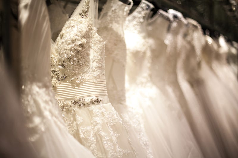 A shopping rack full of white wedding dresses.