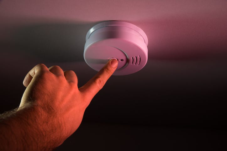 Person Hand Pressing Smoke Detector 