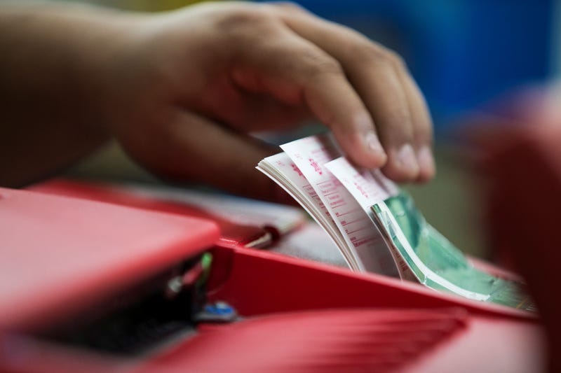 A clerk collects tickets from the Powerball machine
