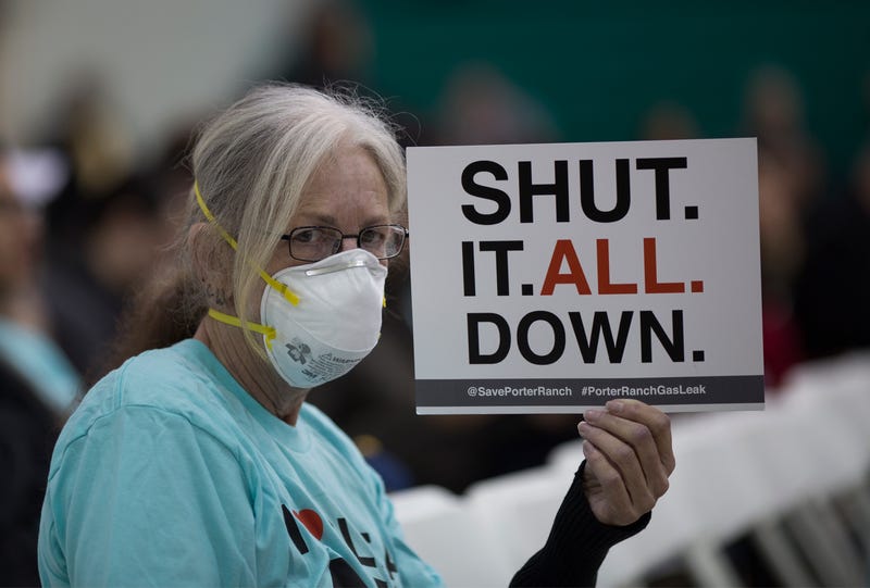 A woman holds a sign while attending a public hearing before the South Coast Air Quality Management District (AQMD) regarding a proposed stipulated abatement order to stop a nearby massive natural gas leak, on January 16, 2016 in Granada Hills, near Porter Ranch, California.